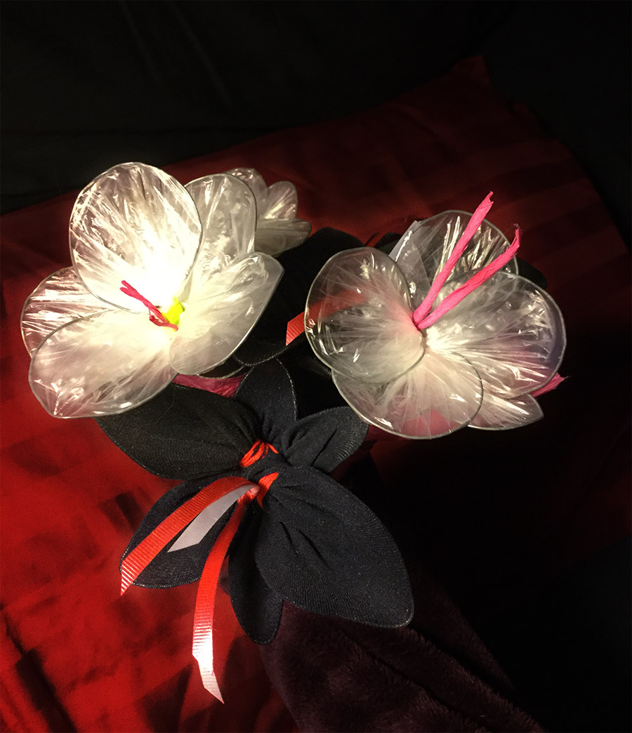 a bouquet with 3 visible flowers, two made of clear plastic and one of black tights.
