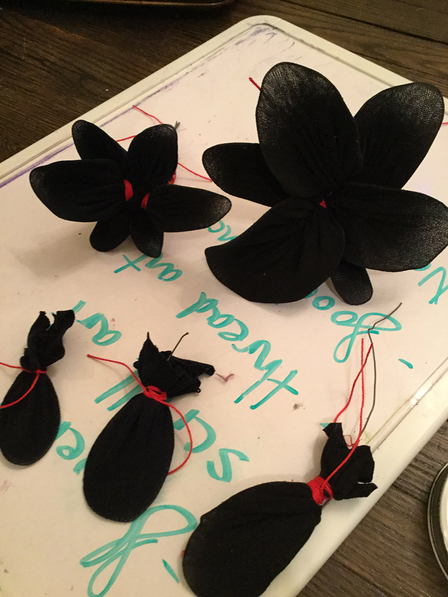 Zhu Hong flowers of 6 petals made of black tights, some of the red string holding them shows in their middle.